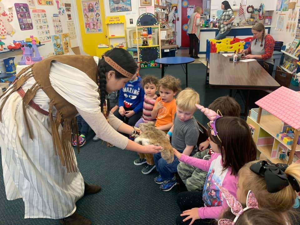 Person in costume showing an animal to children in a classroom