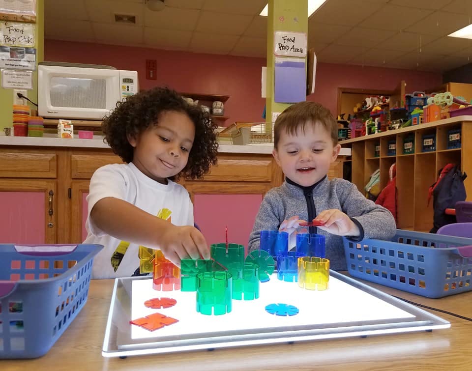 Two children playing with colorful translucent blocks on a light table