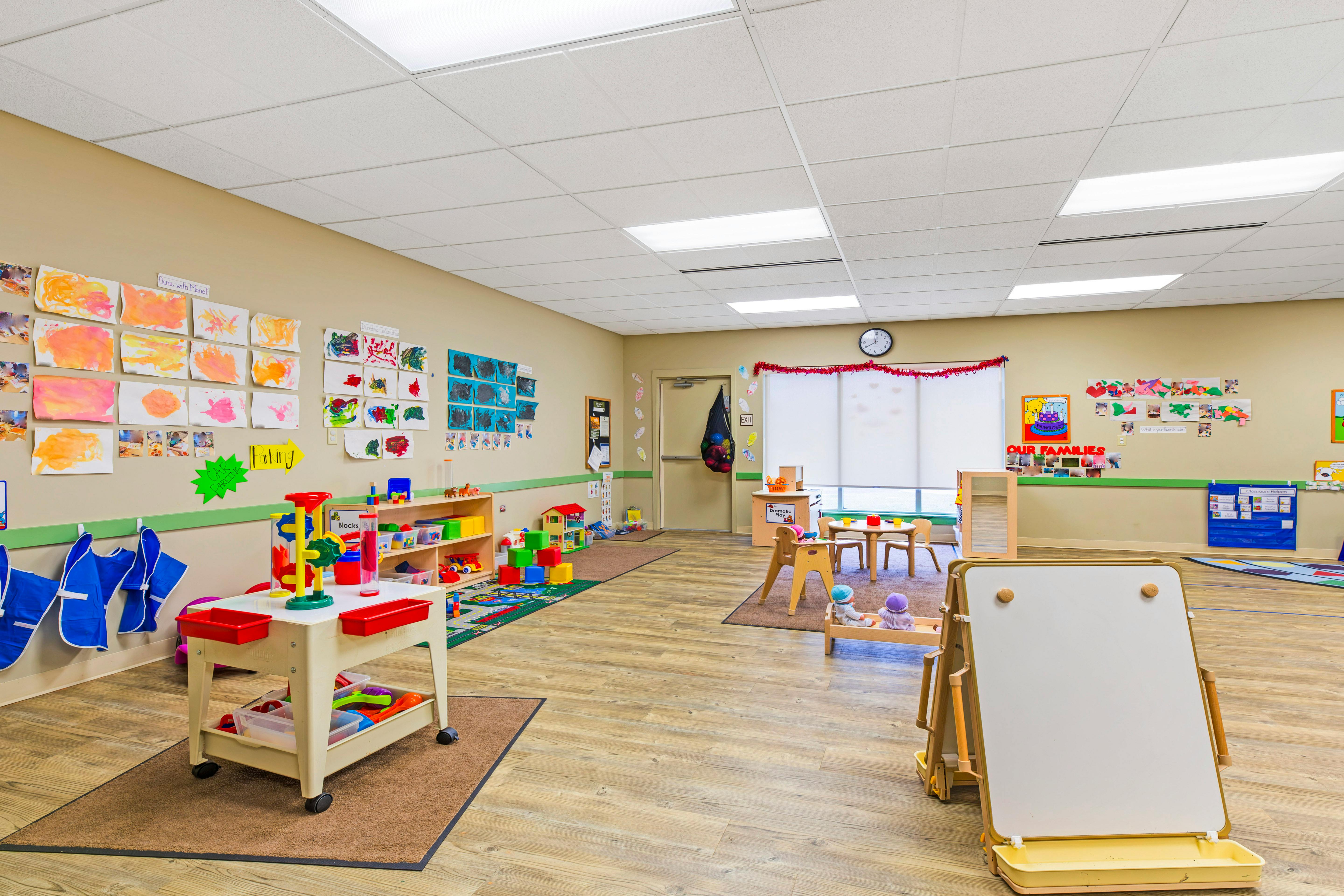 A classroom filled with toys, artwork on the walls, and a small table and chairs