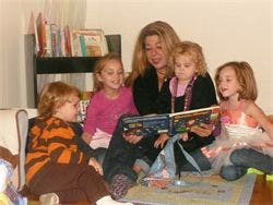 Adult reading a book to four children