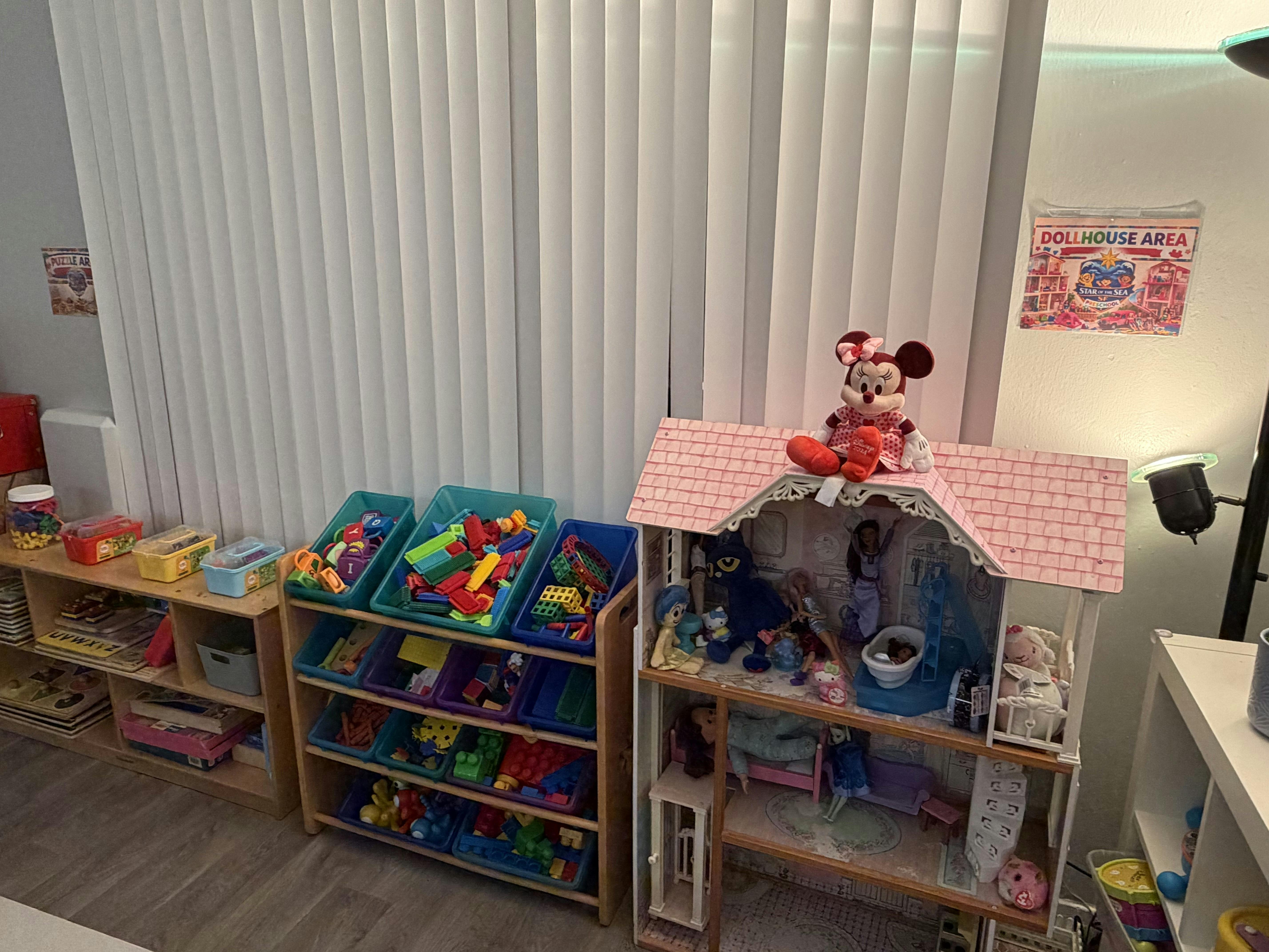 Dollhouse with Minnie Mouse on the roof next to storage shelves with toys