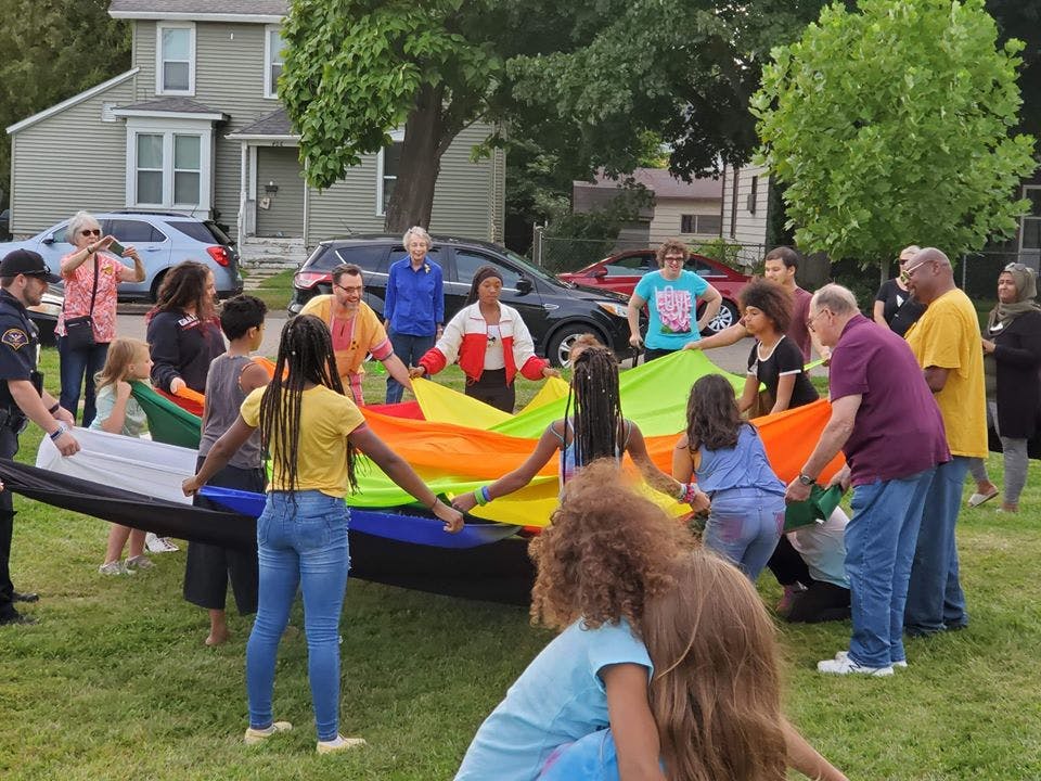 People holding a large colorful parachute outdoors