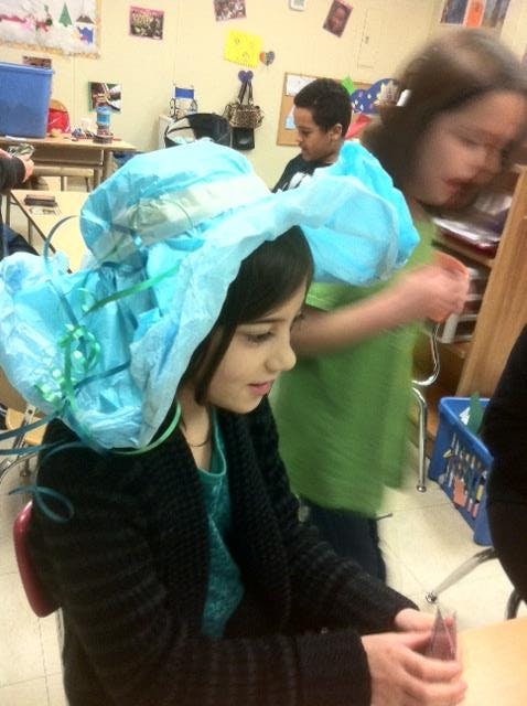 Child wearing a blue hat made from fabric and ribbons