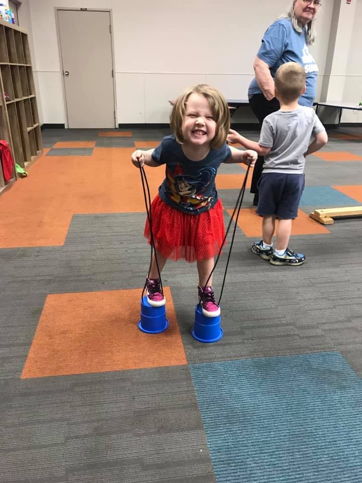 Child standing on blue cup stilts