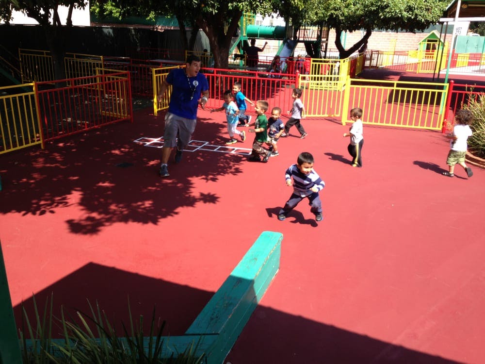 Adult and children playing on a red playground