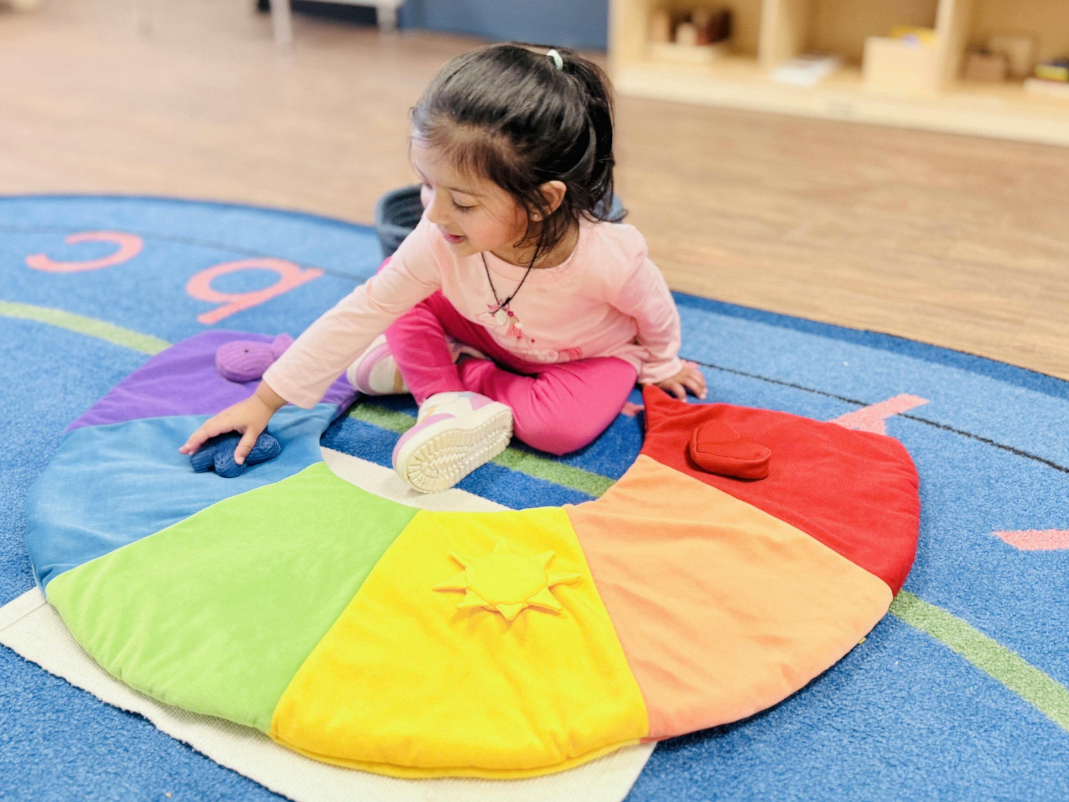 Child playing with a colorful circular playmat in a classroom