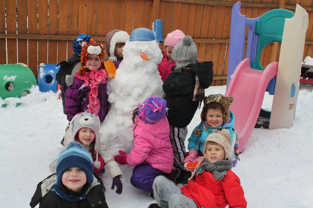 Children playing in snow around a snowman