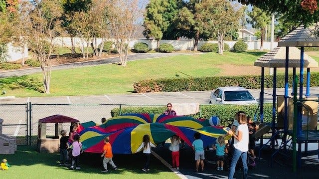 Children playing with a colorful parachute on a playground