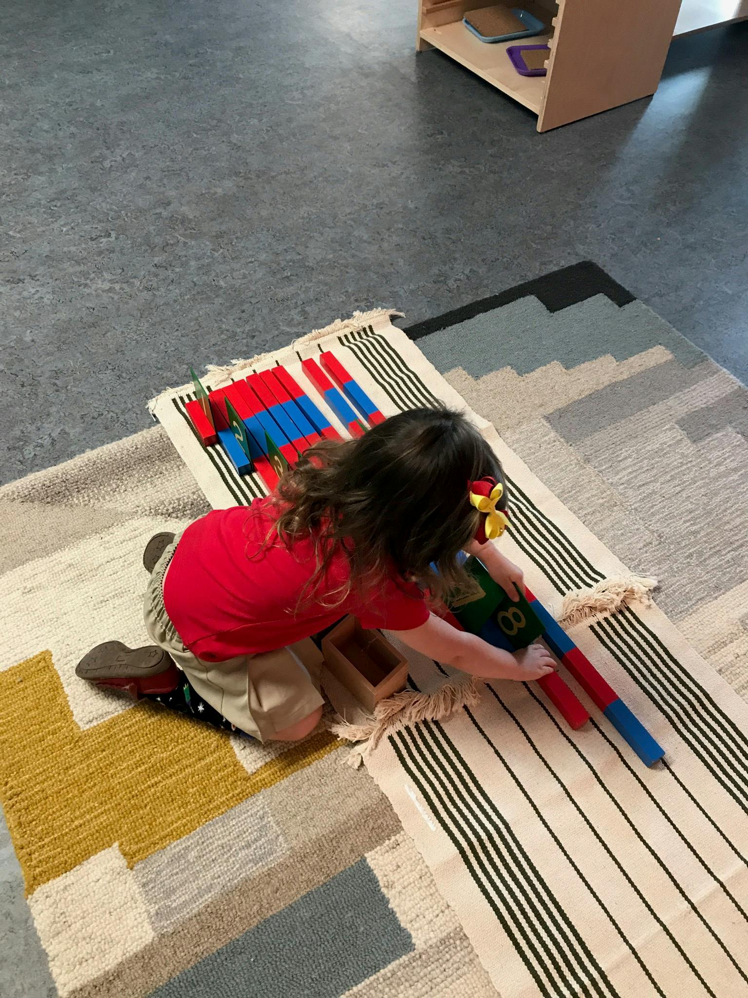 Child kneeling on a rug, playing with colorful blocks