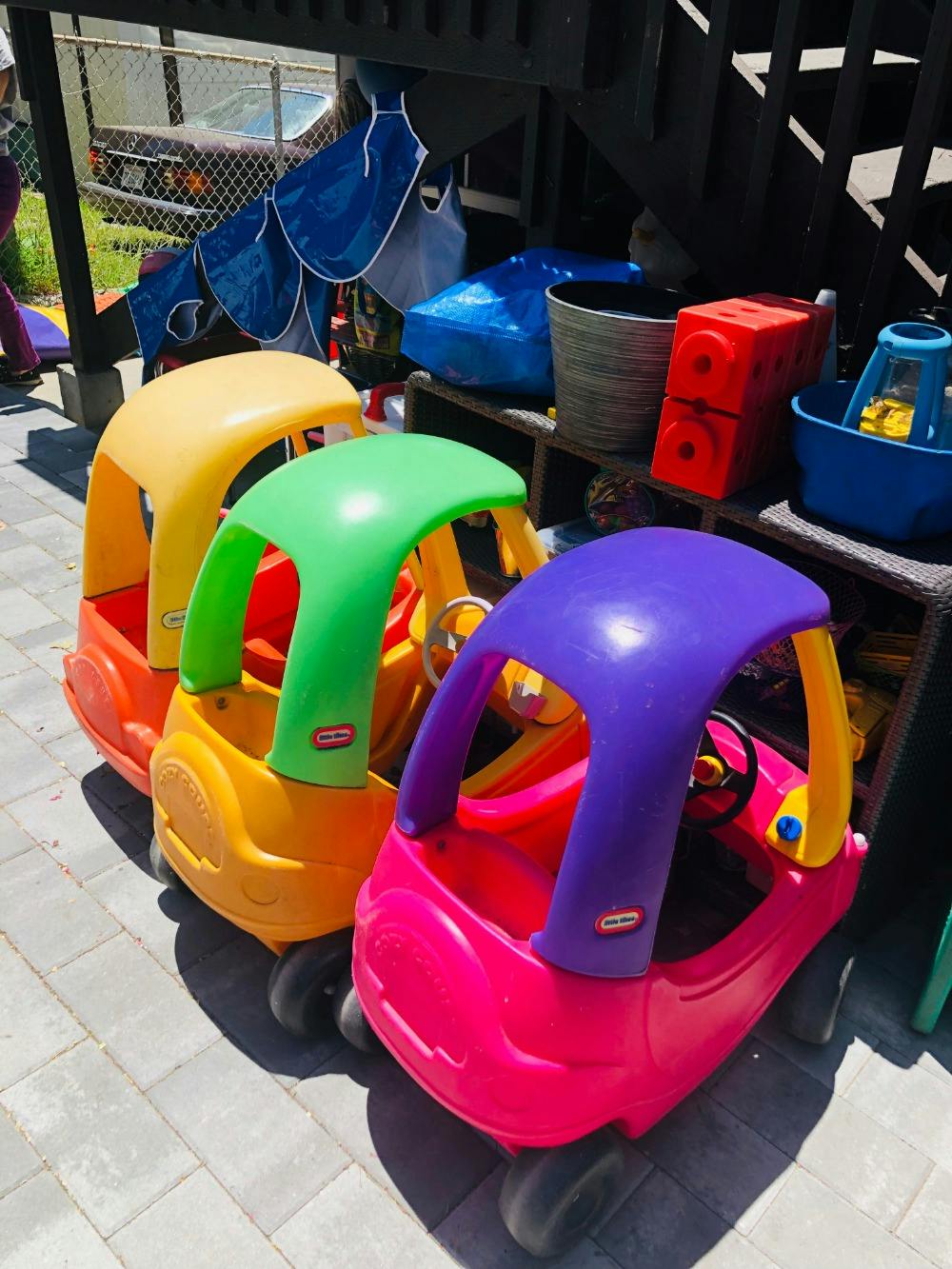 Three colorful toy cars lined up on a paved surface