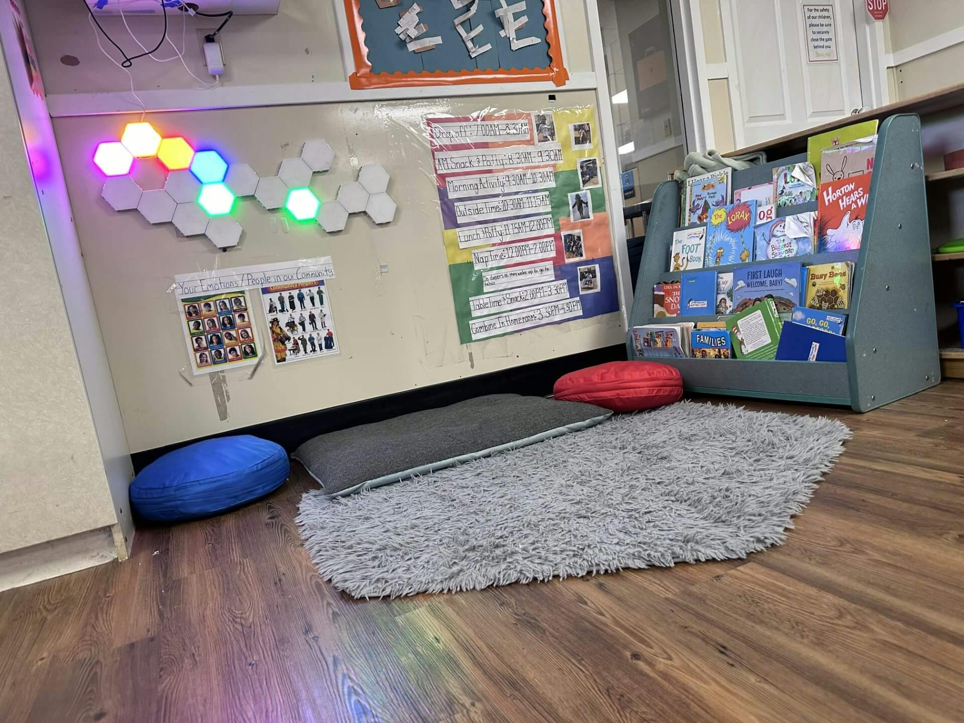 Classroom corner with glowing hexagonal lights, children's books, and floor cushions