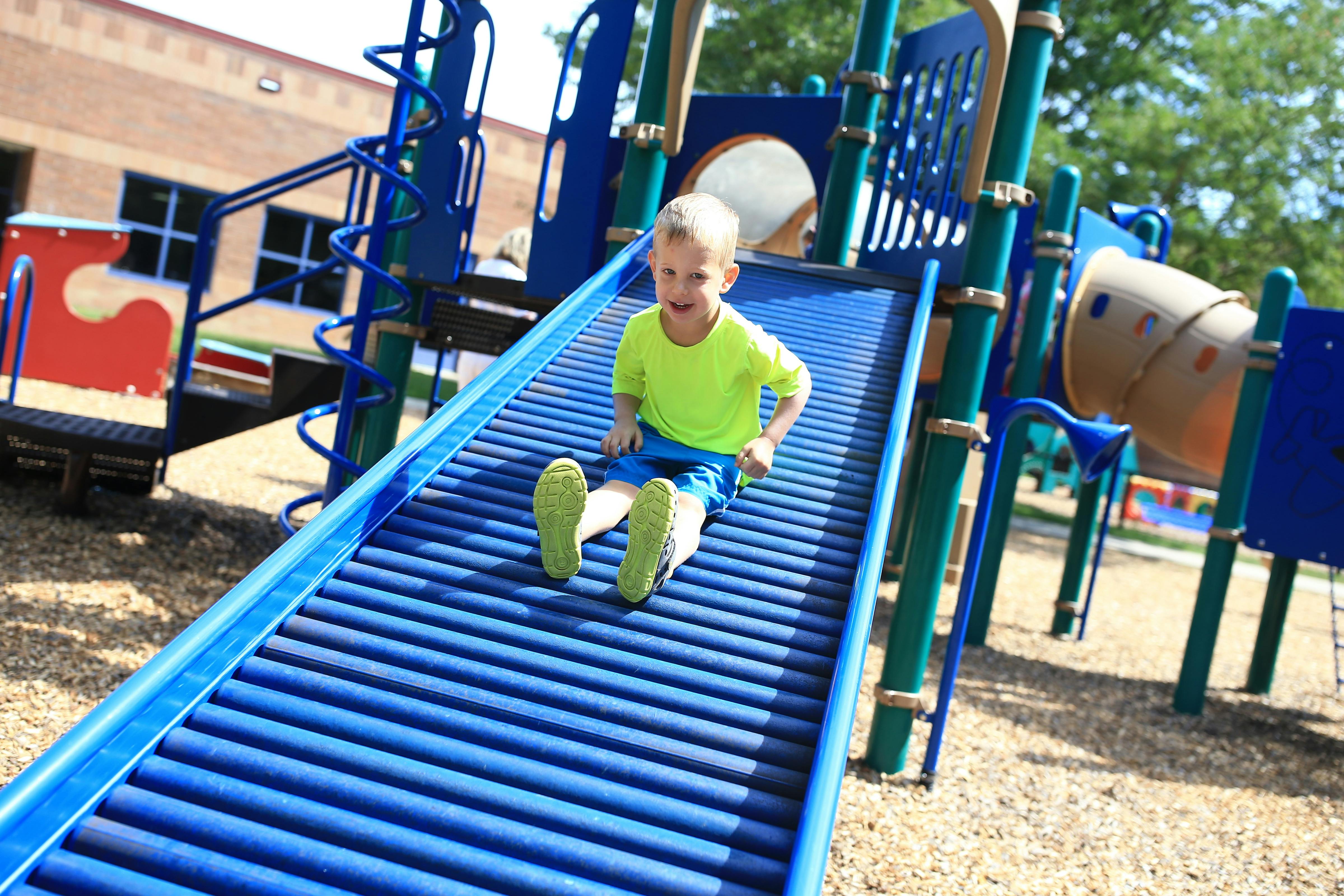 Child on a blue roller slide at a playground