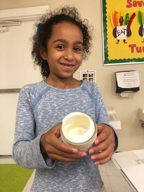 Child holding a jar with a white substance