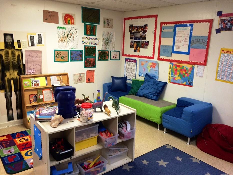 Classroom with child artwork, human skeleton model, bookshelves, and seating
