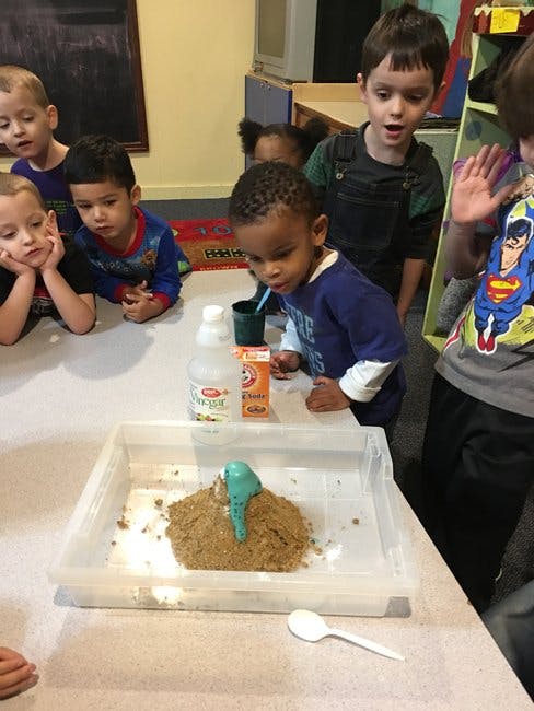 Children watching a science experiment with a sand volcano