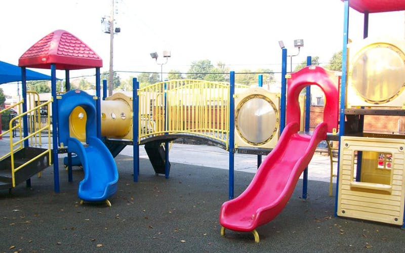 Colorful playground with blue and red slides, a yellow bridge, and tunnels