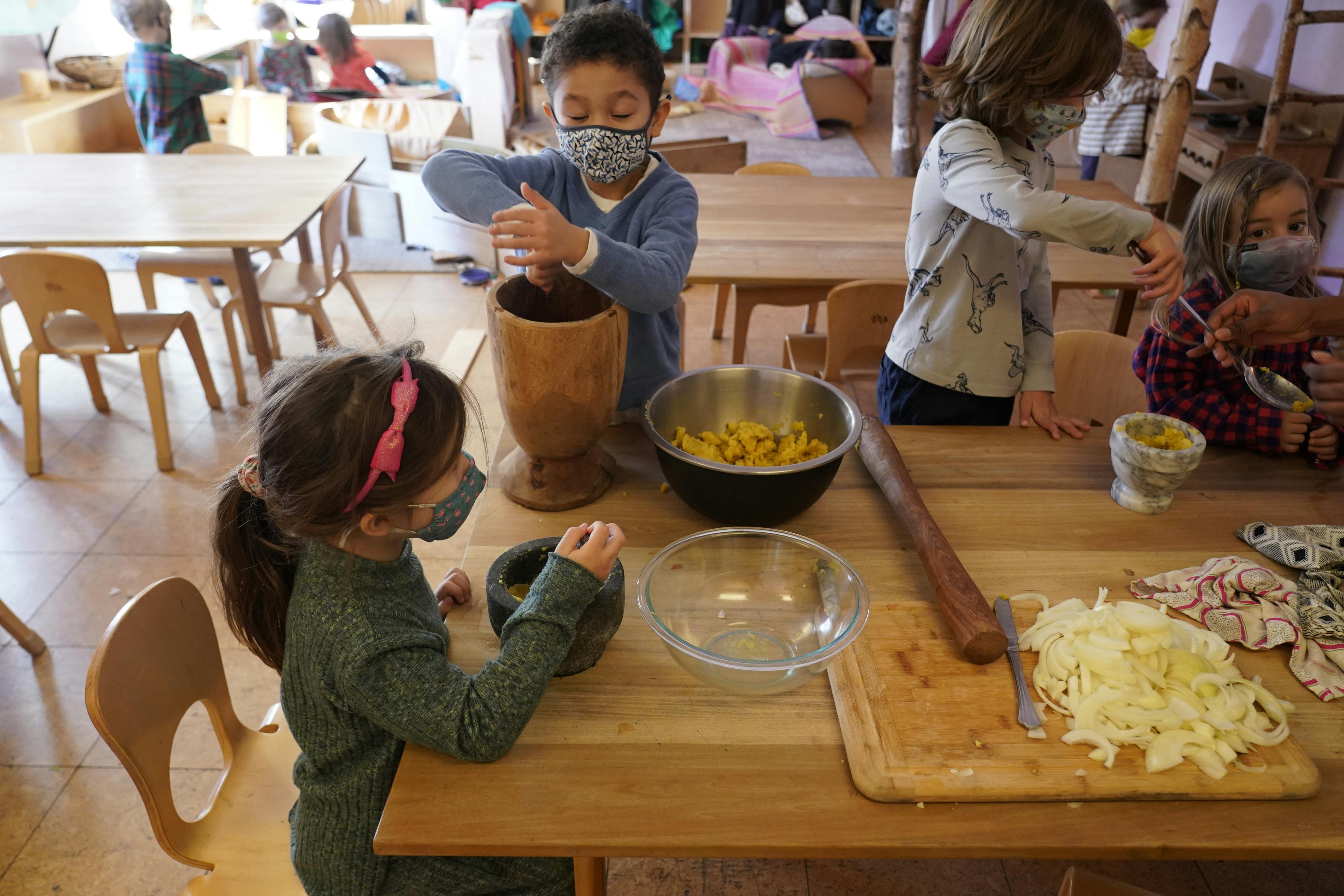 Children in masks preparing food at a table