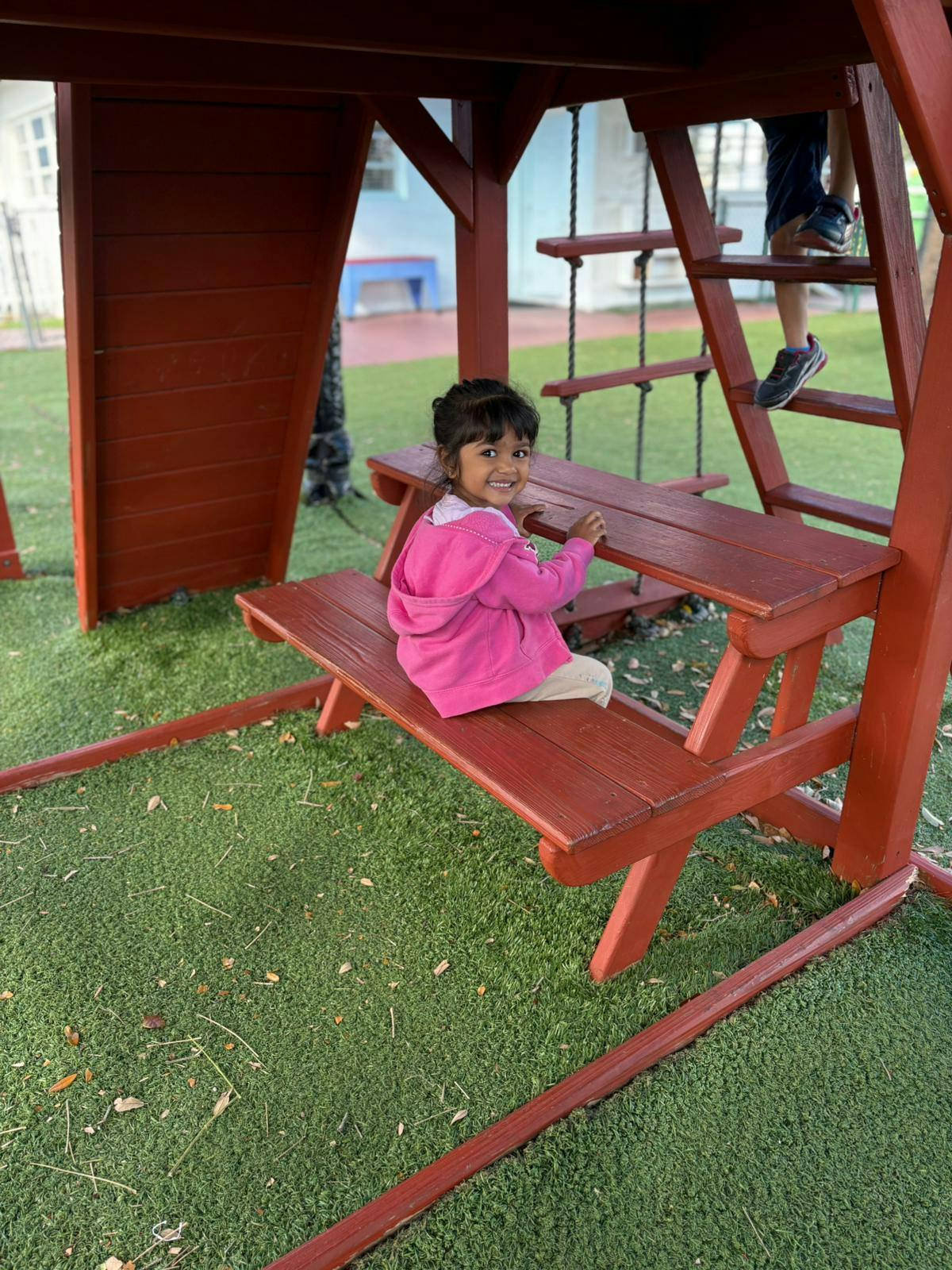 Child sitting on a wooden picnic table at a playground