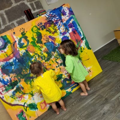 Two children painting on a large canvas