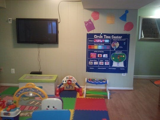 Playroom with a wall-mounted TV, a "Circle Time Center" chart, and colorful toys