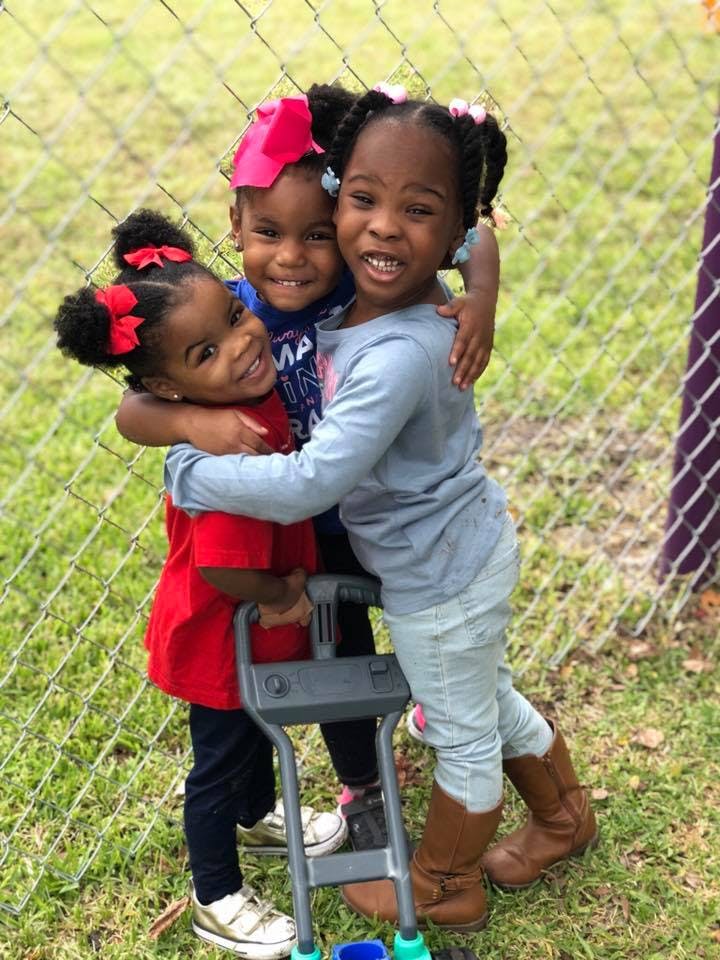 Three children hugging and smiling outdoors