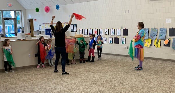 Adult leading children in an activity with scarves