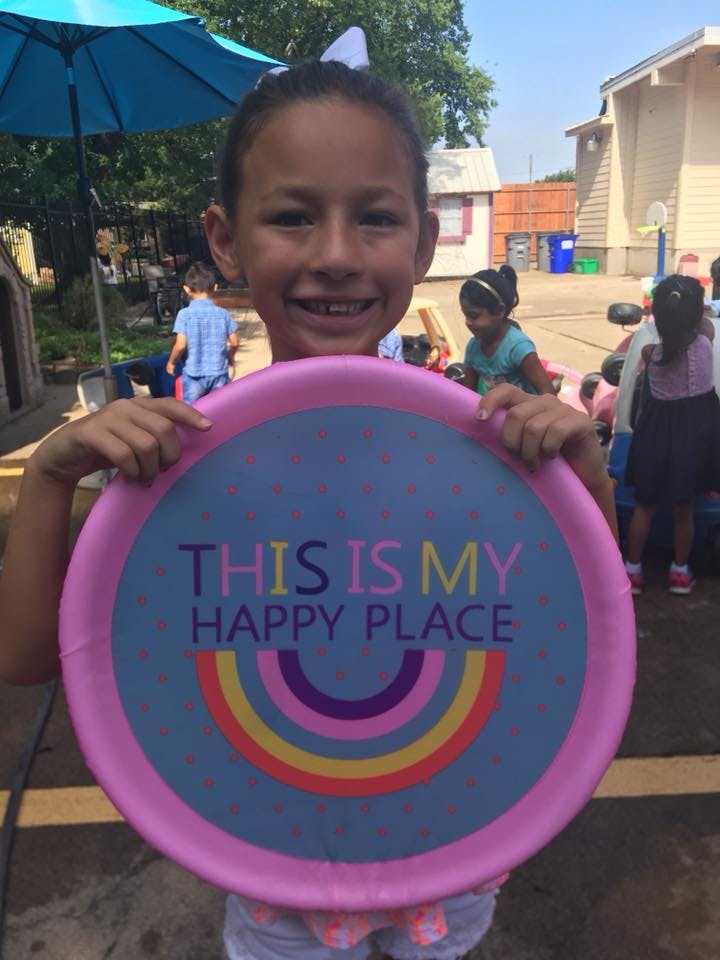 Child holding a sign that reads "THIS IS MY HAPPY PLACE"