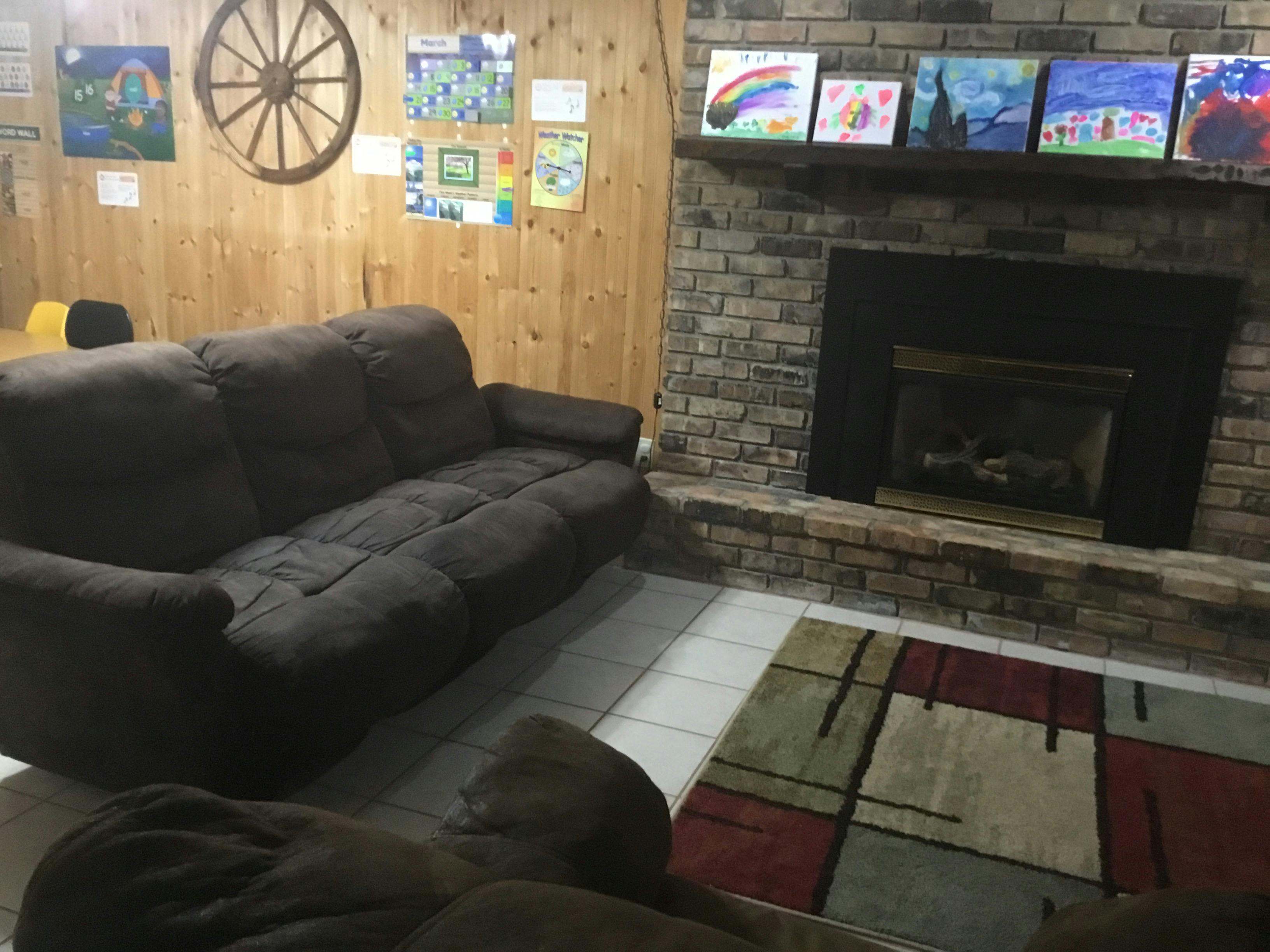 Living room with a brown sofa, fireplace, and colorful rug