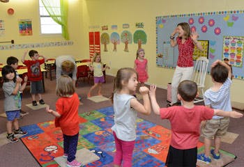 Adult leading children in an activity in a classroom