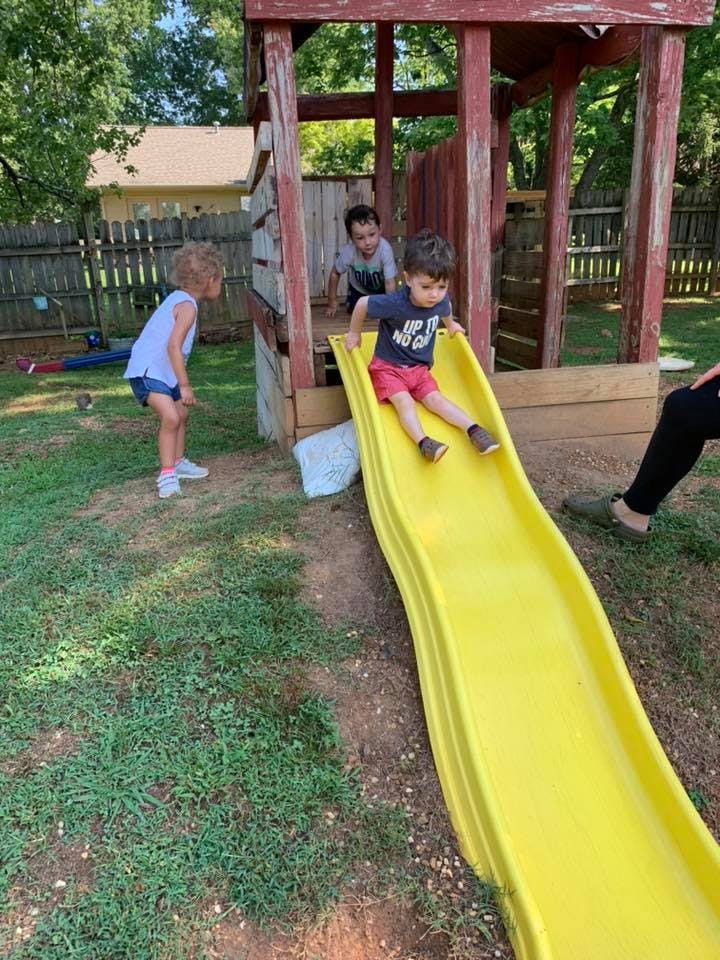 Child sliding down a yellow slide on a playground