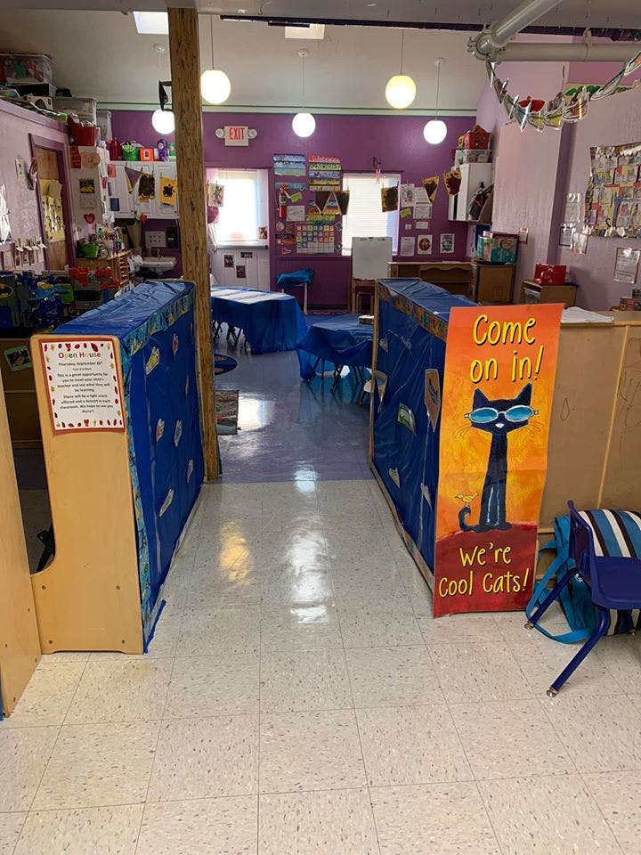 Classroom with blue tables and a sign with a black cat wearing sunglasses