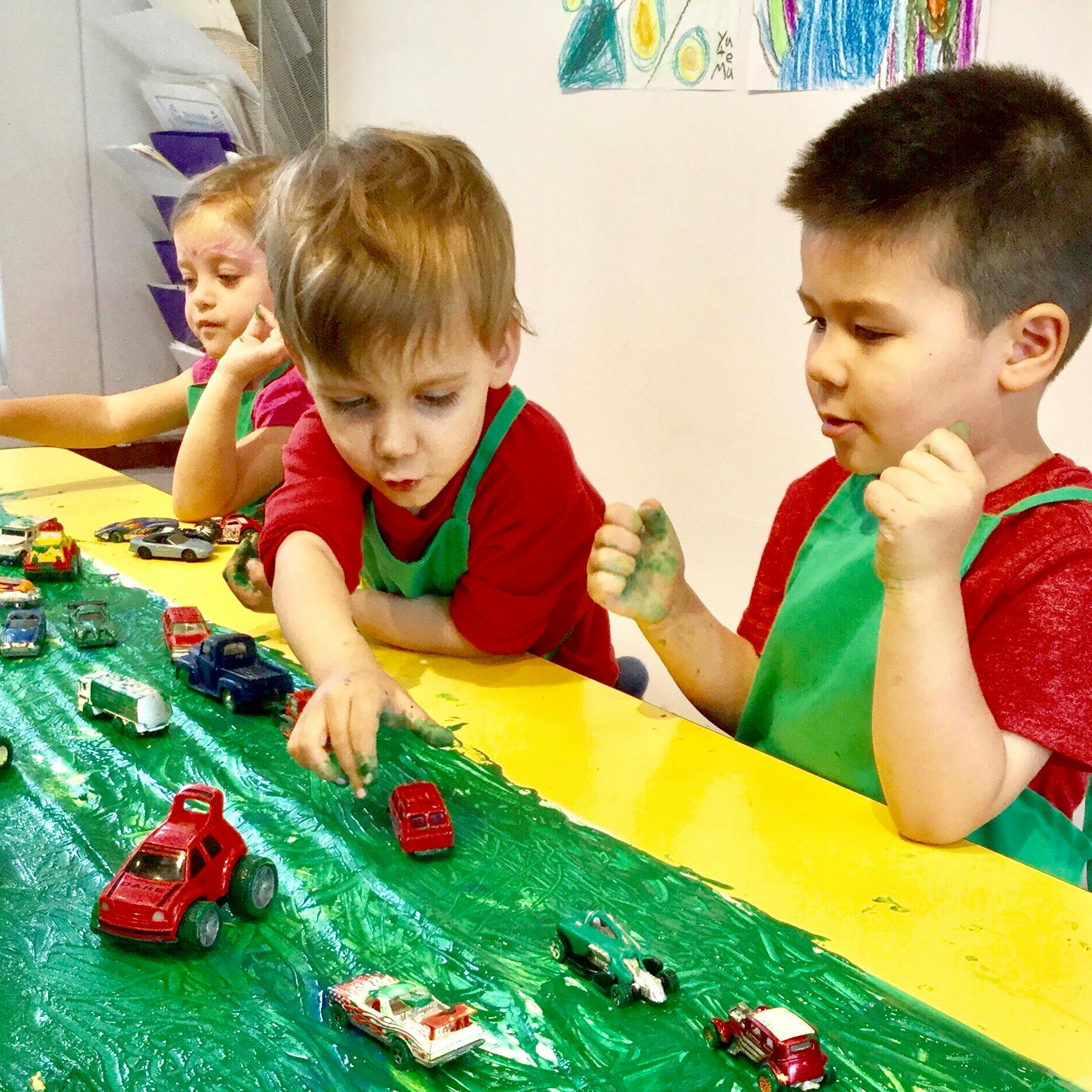 Children playing with toy cars on a green and yellow surface