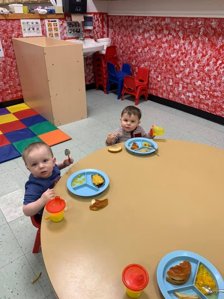 Two children sitting at a table with plates of food