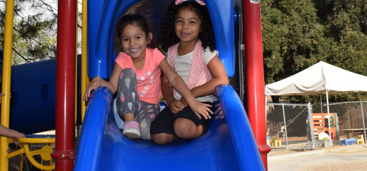 Two children sitting on a blue slide