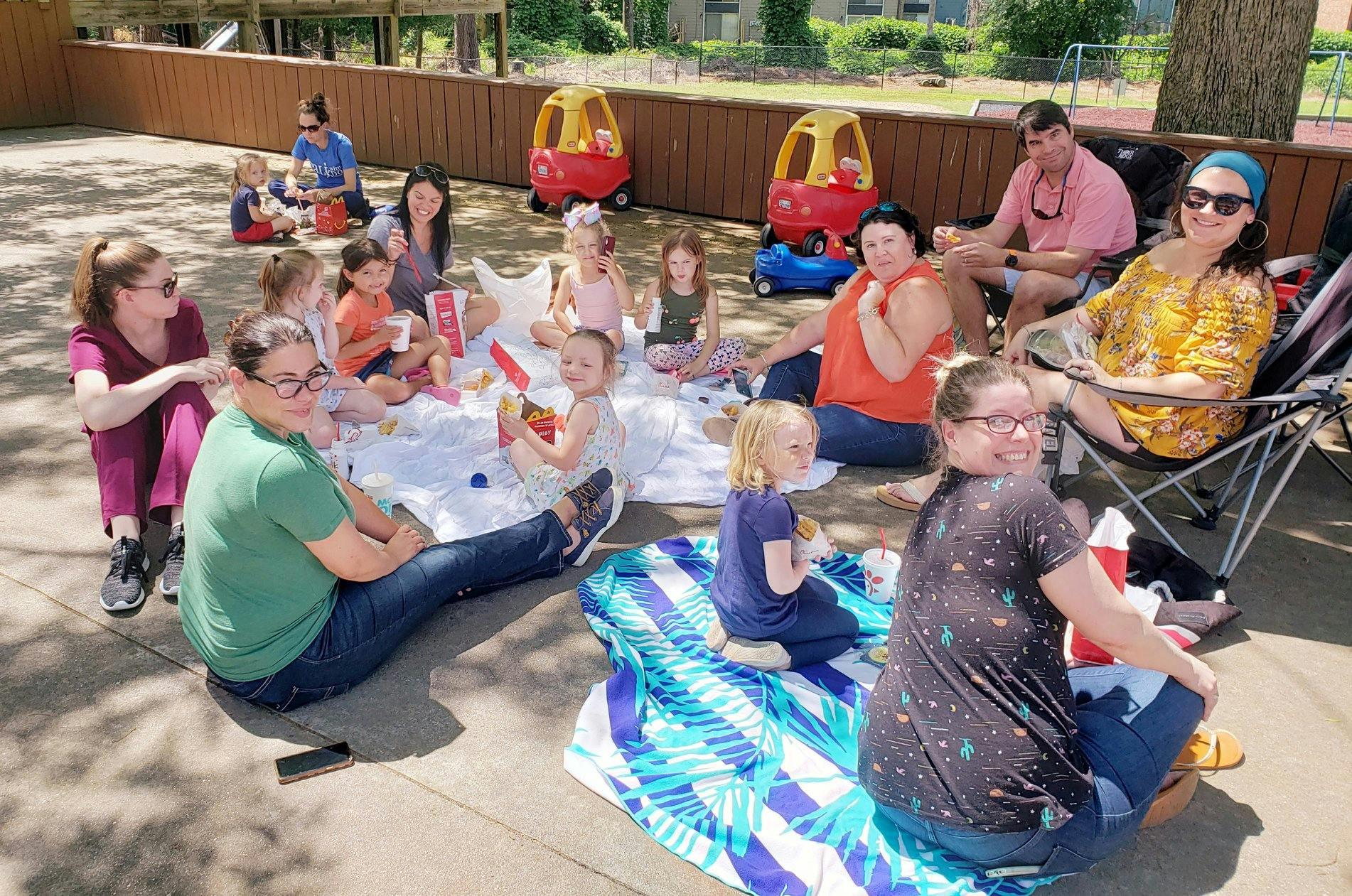 Adults and children sitting on blankets outdoors