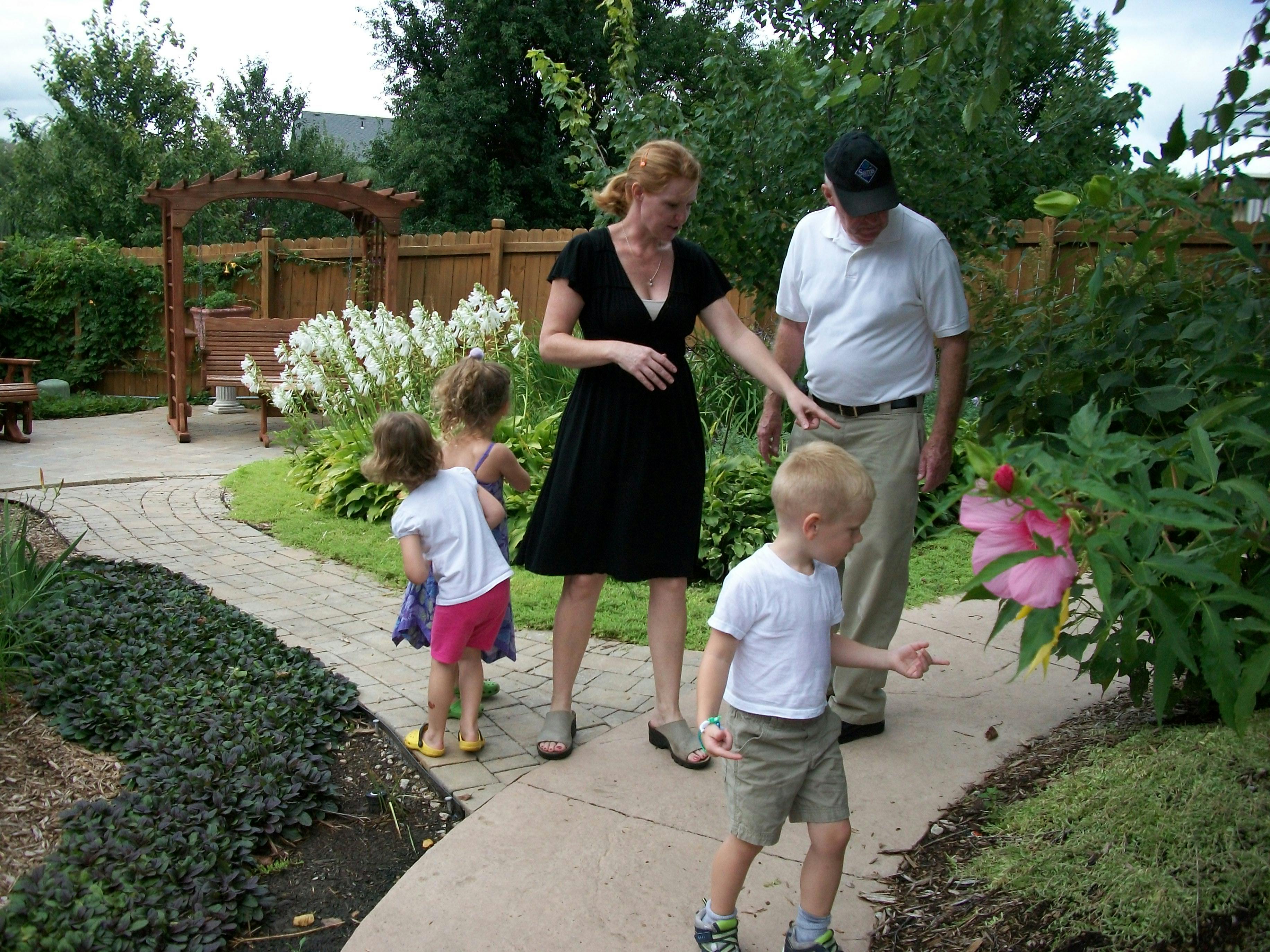 Two adults and two children on a path looking at a pink flower