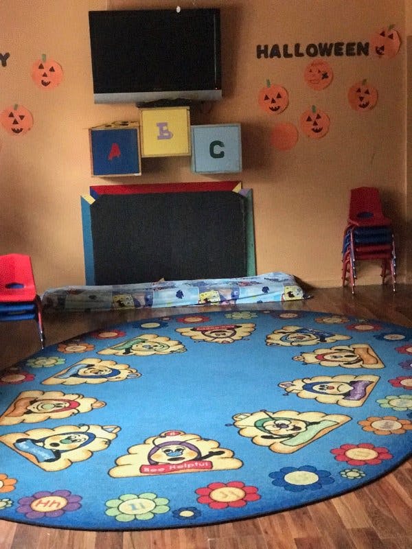 Classroom with a blue circular rug, chalkboard, and Halloween decorations
