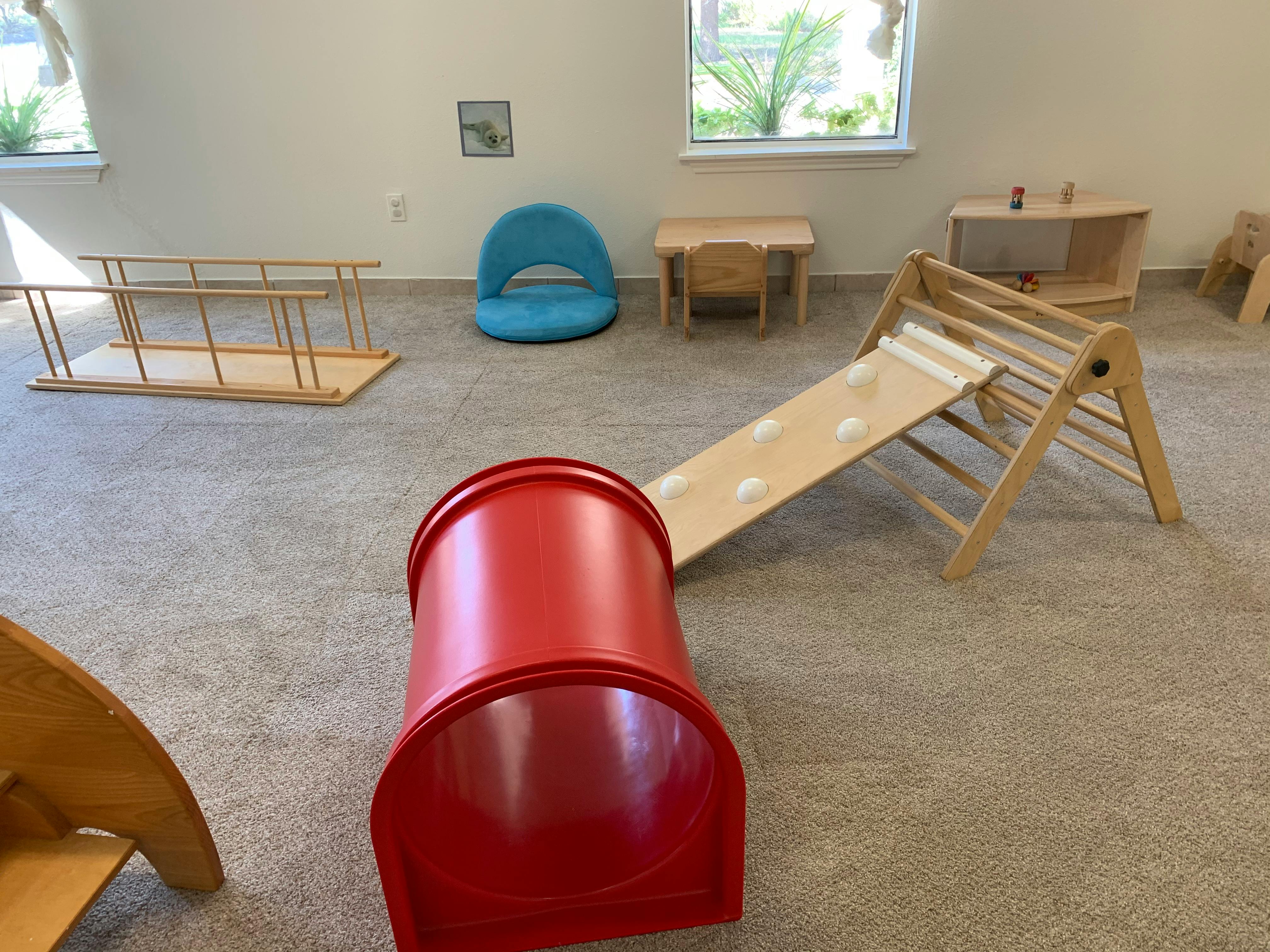 Indoor play area with a red tunnel and wooden slide