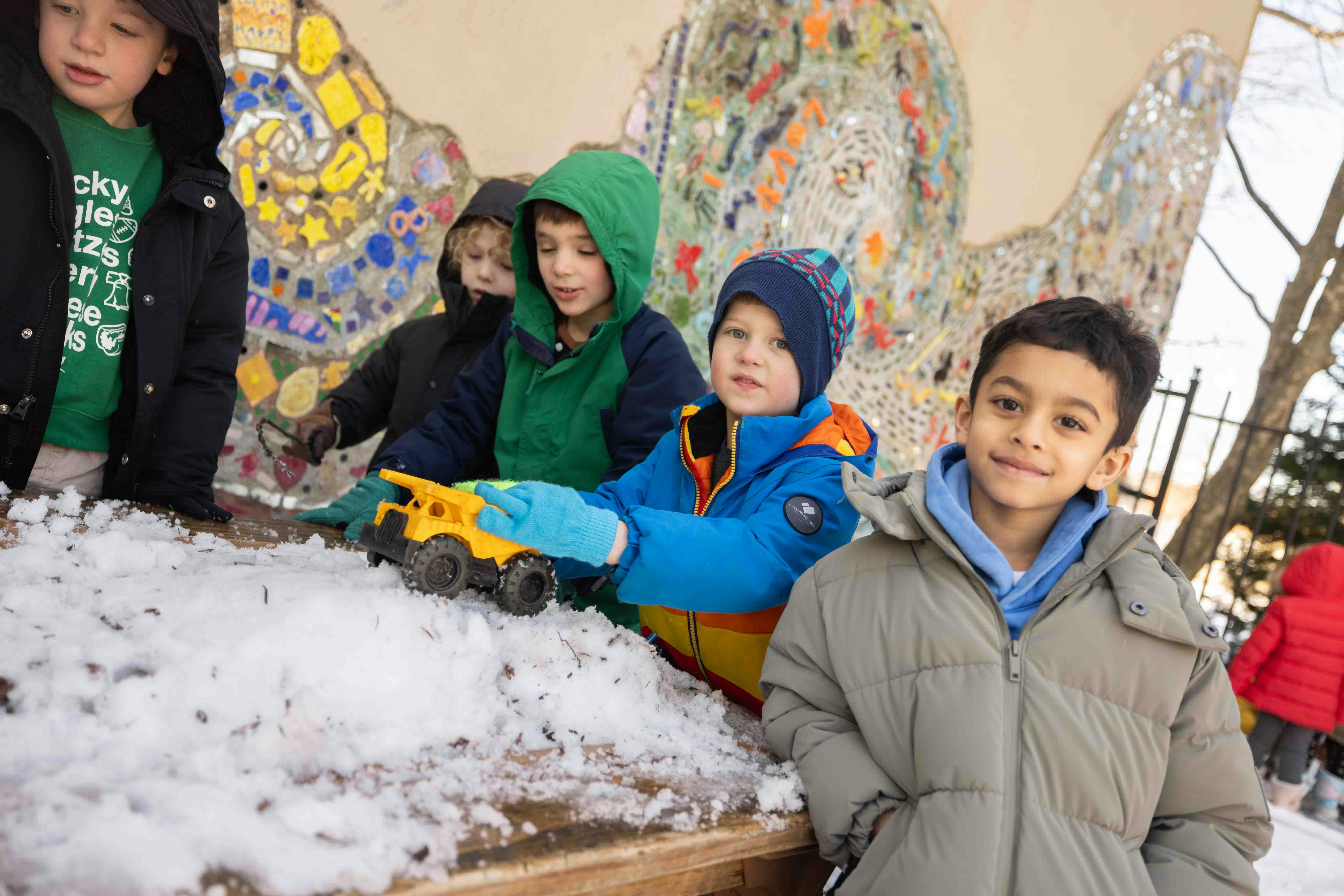 Group of children playing with snow and toys on a wooden surface