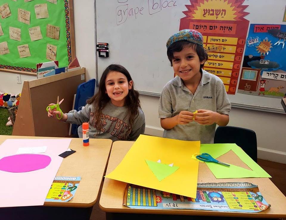 Two children at desks with craft supplies
