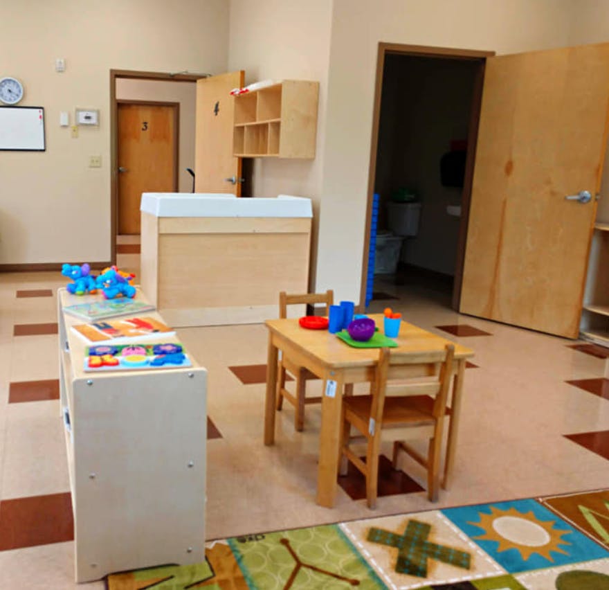 Classroom with small table and chairs, changing station, and toy shelf