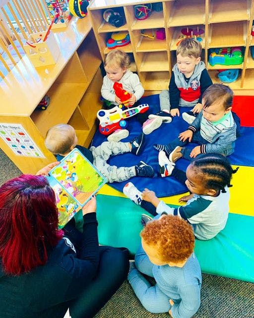 Adult reading a book to children in a classroom