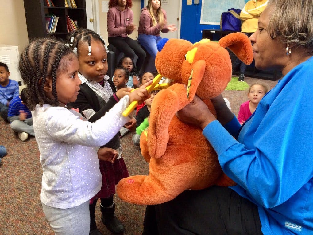 Adult holding a large stuffed animal while children interact with it