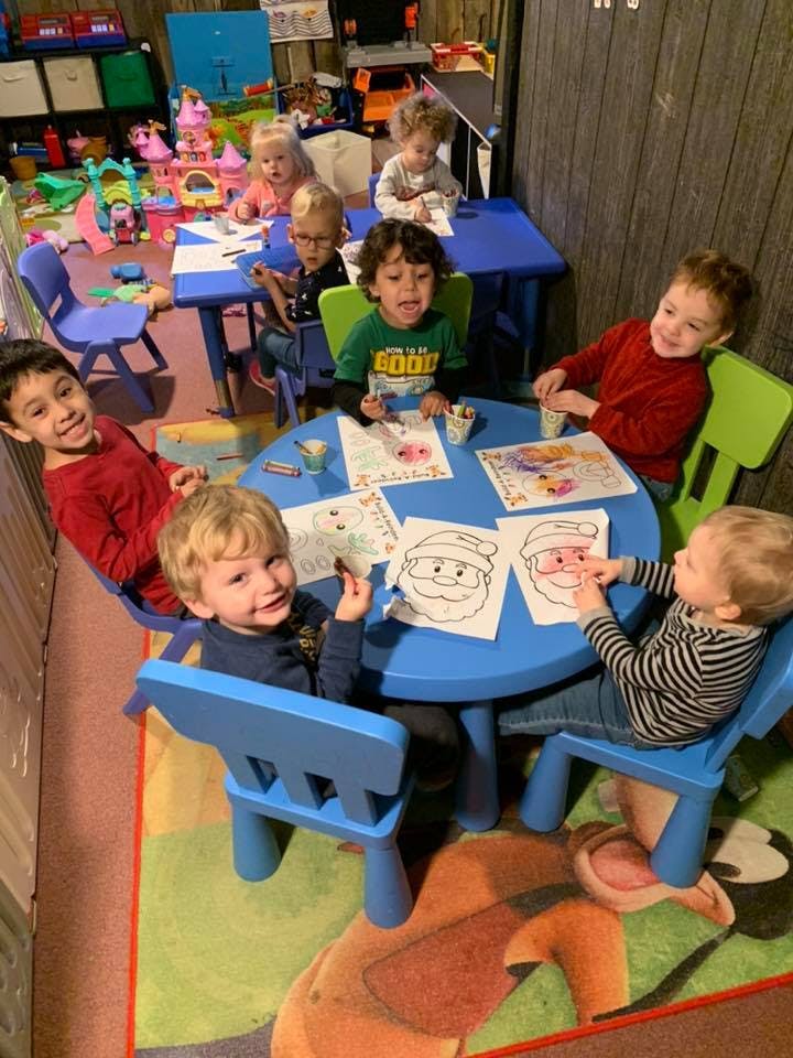 Children sitting at tables coloring pictures in a classroom