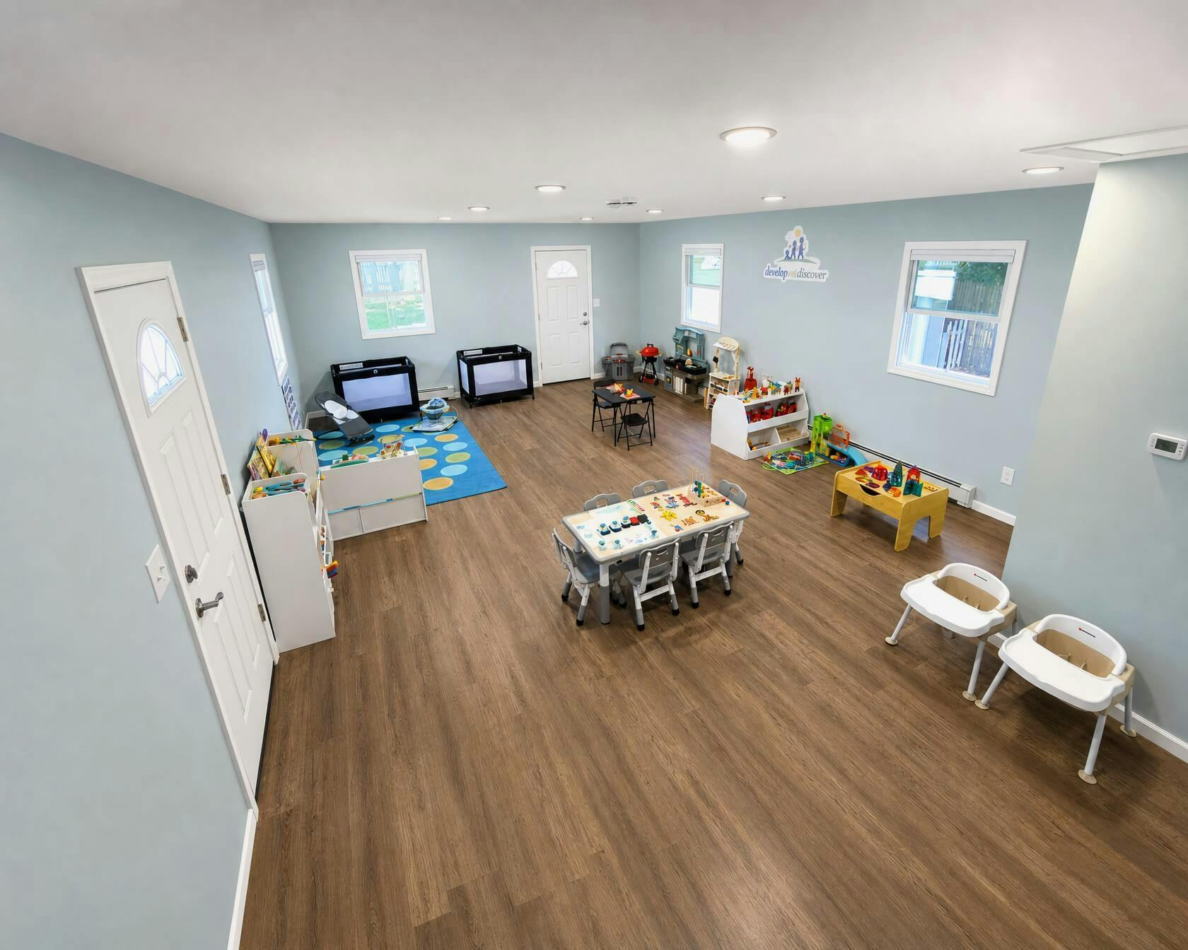 Spacious daycare room with tables chairs toys and play equipment