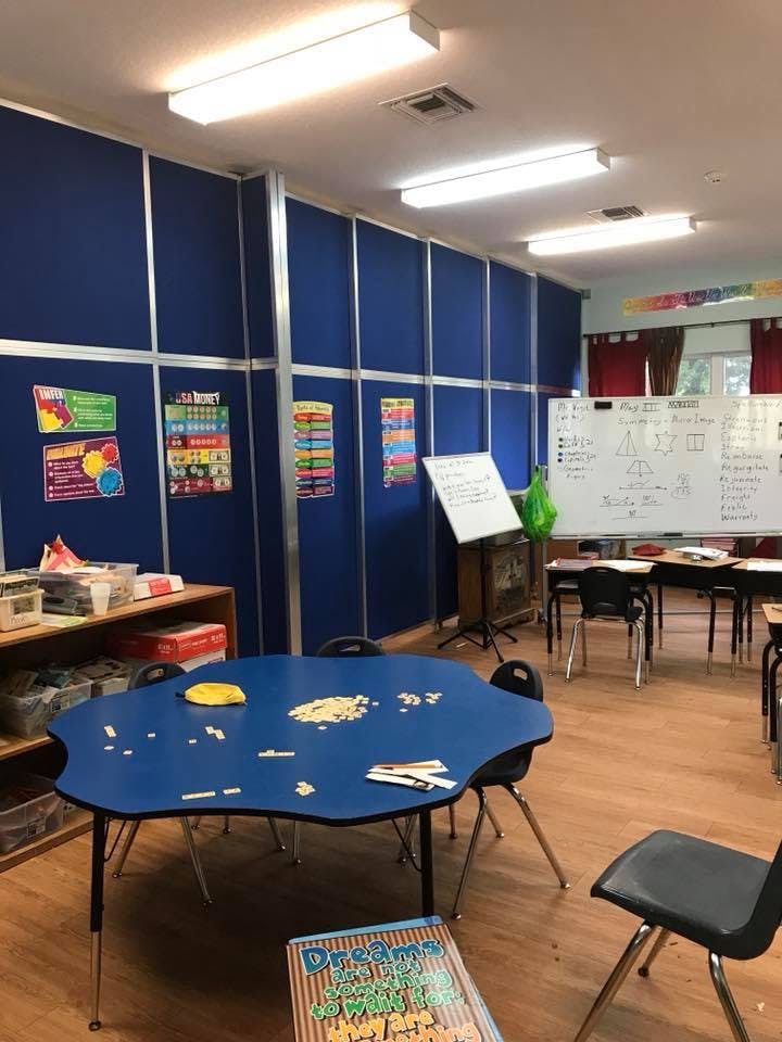 Classroom with blue walls, a blue table, and a whiteboard