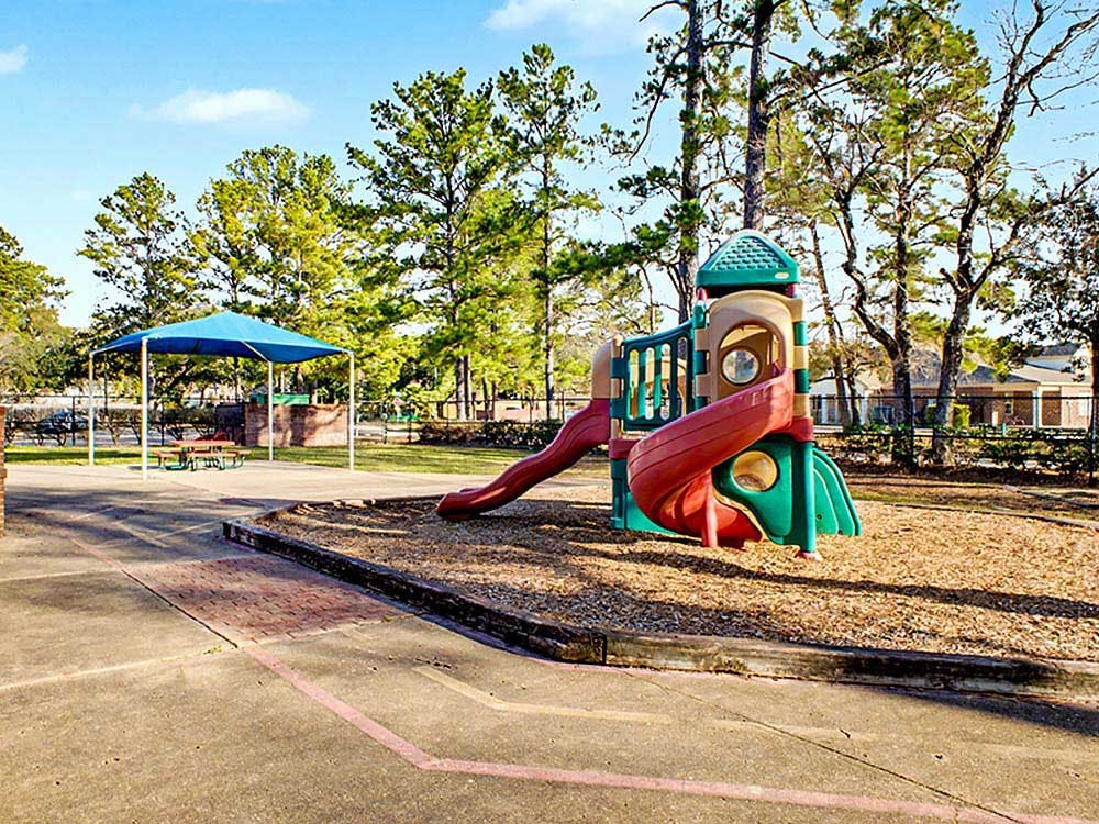 Playground with playset, slides, and blue canopy over picnic tables