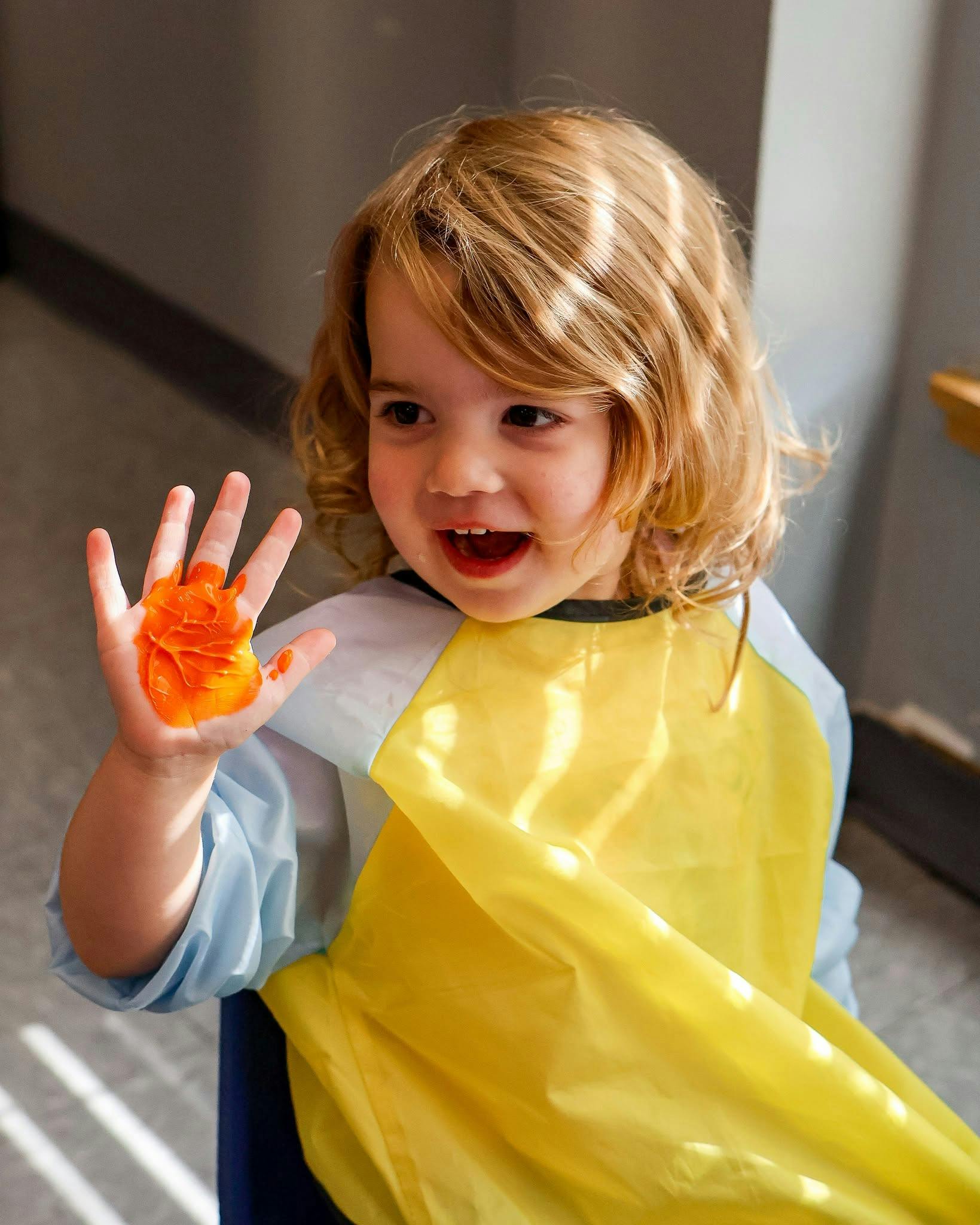 Child wearing an apron with paint on their hand