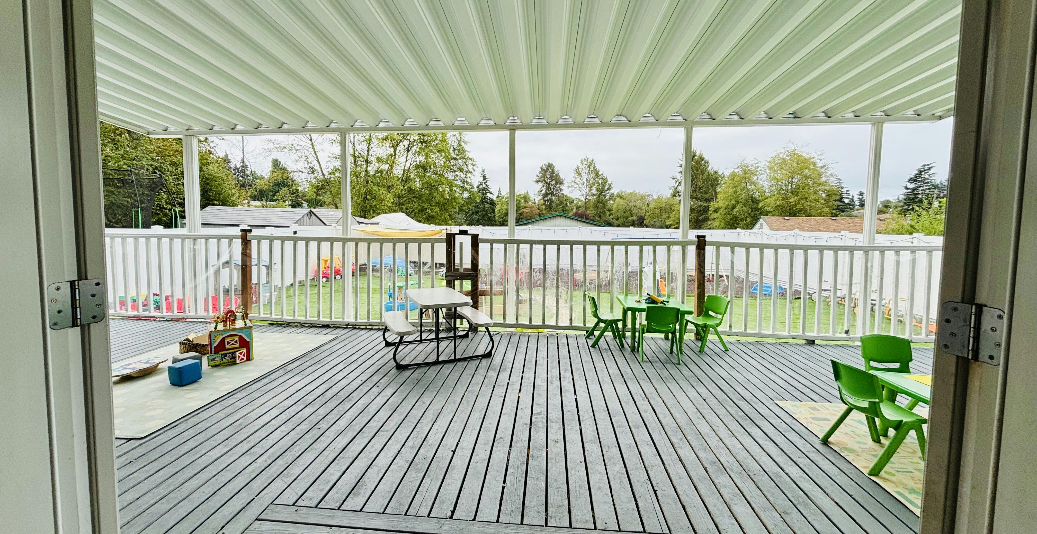Outdoor deck with small tables and chairs overlooking a playground
