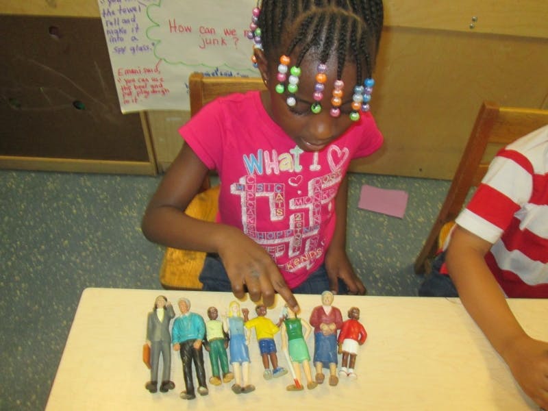 Child pointing at a group of small figurines on a table